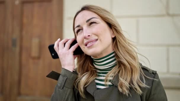 Молода красива іспаномовна жінка посміхається впевнено слухаючи аудіо повідомлення зі смартфоном на вулиці
 - Кадри, відео
