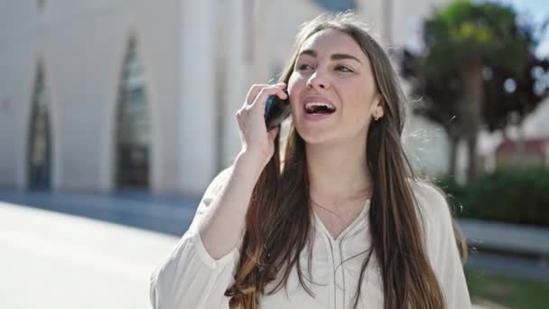 Young beautiful hispanic woman smiling confident talking on smartphone at street - Video, Çekim