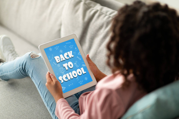 E-öğrenme, online eğitim konsepti. Afro-Amerikan okul kızlarının evdeki kanepede oturup dijital tablet kullanırken çekilen omuz üstünden ekrana yansıyan metinler, kopyalama alanı, kolaj - Fotoğraf, Görsel