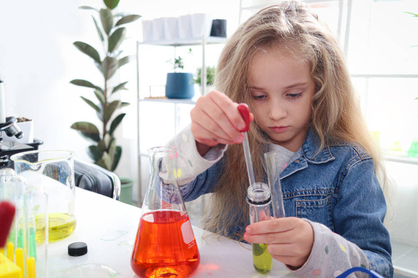Uzun sarı saçlı ilkokul kızı laboratuvarda kimya bilimi deneyi yapıyor. Renkli test tüpleri ve laboratuvar ekipmanları olan sevimli bilim adamı çocuk sınıfta biyoloji ve kimya öğreniyor.. - Fotoğraf, Görsel