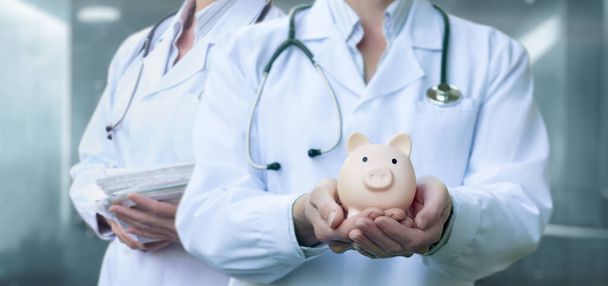 Um grupo de médicos mostra um banco porquinho em um fundo borrado em uma policlínica. - Foto, Imagem