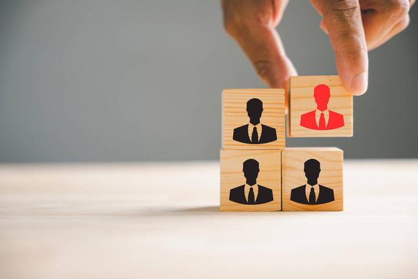 A hand is seen choosing man people icons with on cube wooden toy blocks stacked. Represents the idea of teamwork, leadership, and corporate strategy in achieving business goals. - Foto, immagini