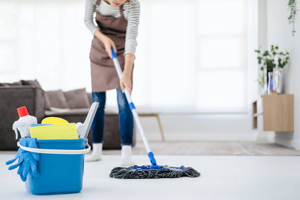Cropped image of beautiful young woman in protective gloves using a flat wet-mop while cleaning floor in the house - Fotografie, Obrázek