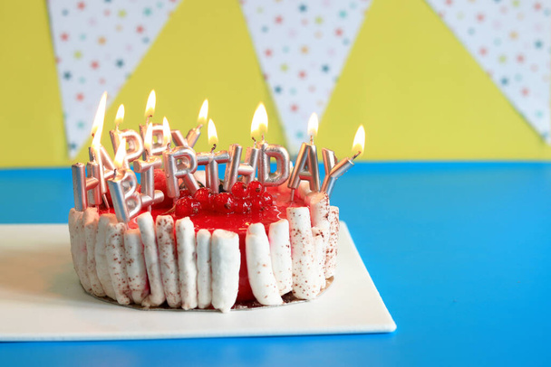 Geburtstagstorte. Kuchen mit brennenden Kerzen auf hellem Hintergrund. Alles Gute zum Geburtstag! Festlicher Kuchen vor festlichem Hintergrund mit Fahnen - Foto, Bild