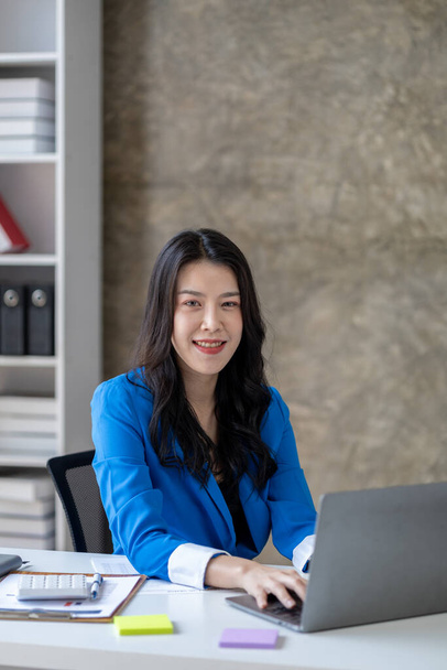 Kurumsal ofiste çalışan genç ve güzel Asyalı bir kadın, iş kadını, şirket kurma işini büyütmek ve modernize etmek için özenle çalışıyor, şirketin pazar ve mali verilerini analiz ediyor.. - Fotoğraf, Görsel