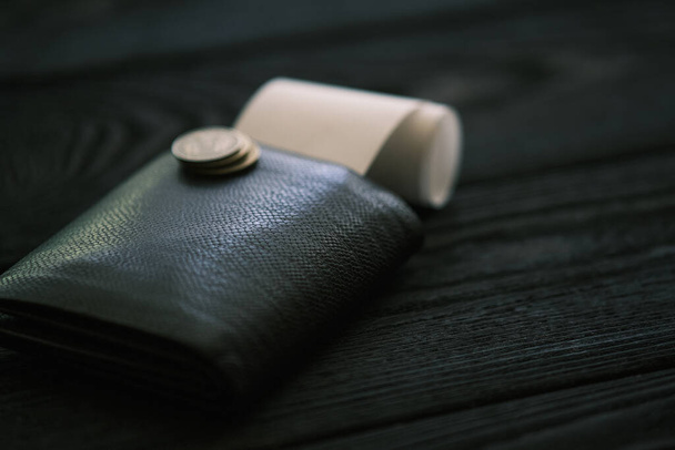 Un sac à main en cuir et une petite pile de pièces sur une table en bois noir, concept financier - Photo, image