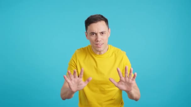 Video in studio with blue background of a man advises calm with the hands because everything is under control. - Footage, Video