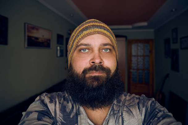 A man with a beard wearing a striped hat and shirt, looking up into the camera - Photo, Image