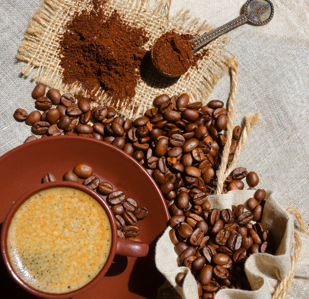 A cup of espresso coffee on a background of ground beans and burlap. Arabica is the most common type of coffee. - Photo, Image