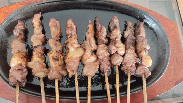 kambing sate lub szaszłyki mięsa koziego serwowane na metalowej płycie grzejnej z sosem orzechowym w Dżakarcie w Indonezji. Fotografia żywności - Zdjęcie, obraz