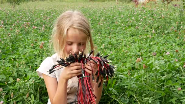Una chica está oliendo un ramo de flores ensambladas a partir de conectores eléctricos. - Metraje, vídeo
