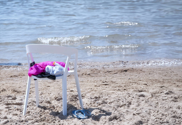  White chair with clothes on a sandy beach against the backdrop  - Foto, immagini