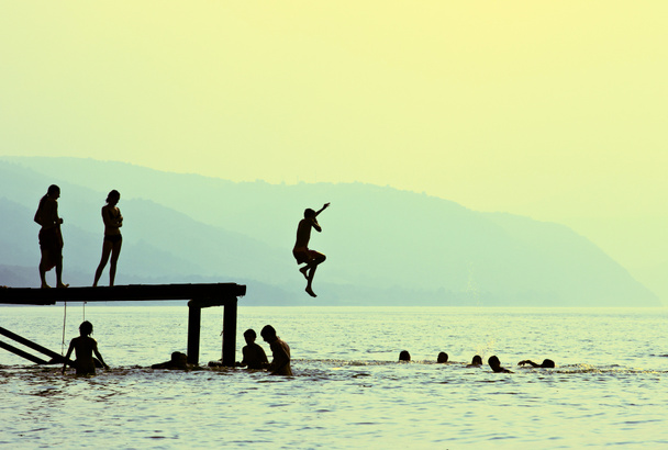 Silhouettes d'enfants qui sautent du quai sur le lac
 - Photo, image