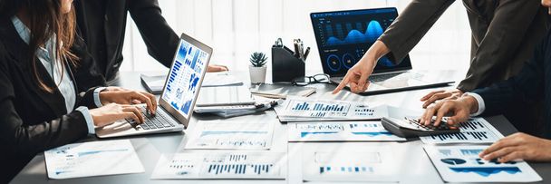 Panorama shot analyst team utilizing BI Fintech to analyze financial report with laptop. Businesspeople analyzing BI data dashboard displayed on laptop screen for business insight. Prodigy - Φωτογραφία, εικόνα