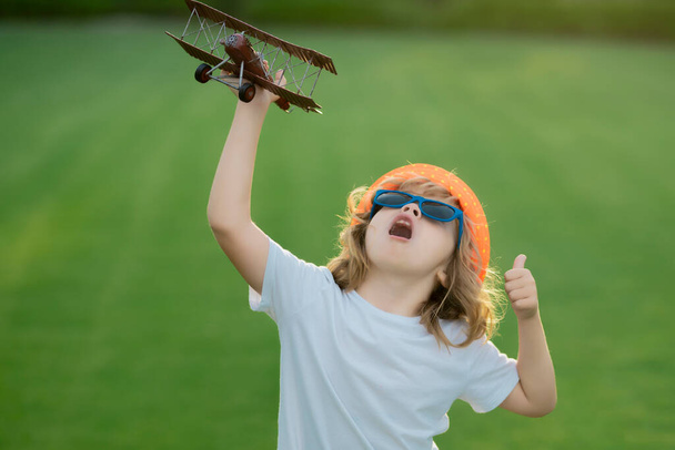 Children day. Kid pilot aviator with with paper wings dreams of traveling in summer in park outdoor - Photo, Image