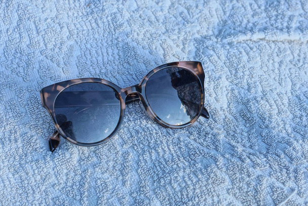 one plastic brown sunglasses lies on a white cloth - Φωτογραφία, εικόνα