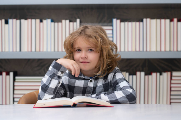 Dziecko w bibliotece czyta książki. Uczeń wybiera książkę w szkolnej bibliotece. Literatura dziecięca do czytania. Dzieciak w księgarni. Uczę się z książek. Edukacja szkolna. Wracamy do szkoły. - Zdjęcie, obraz