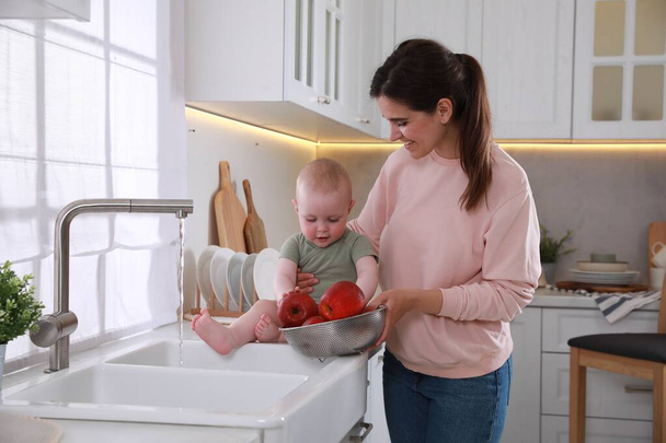 Mother and her cute little baby spending time together in kitchen - Φωτογραφία, εικόνα