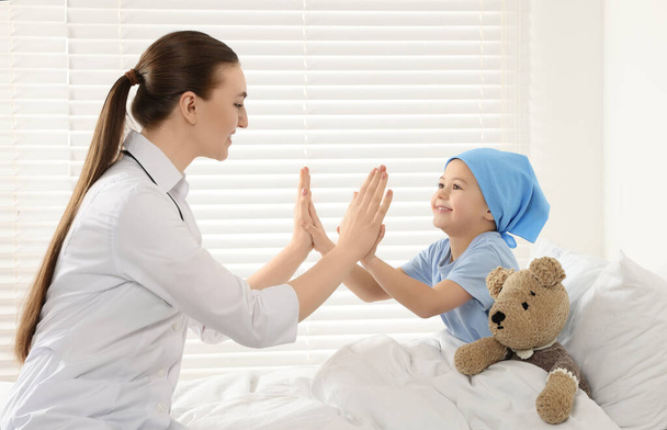 Childhood cancer. Doctor and little patient playing clapping game with hands in hospital - Valokuva, kuva