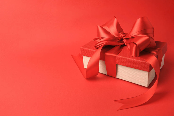 Beautiful gift box with bow on red background. Space for text - Photo, image