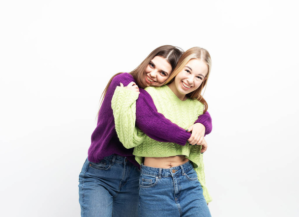 Two cheerful young women hugging and having fun together over white background, the concept of friendship and youth. lifestyle and people concept. - Fotografie, Obrázek