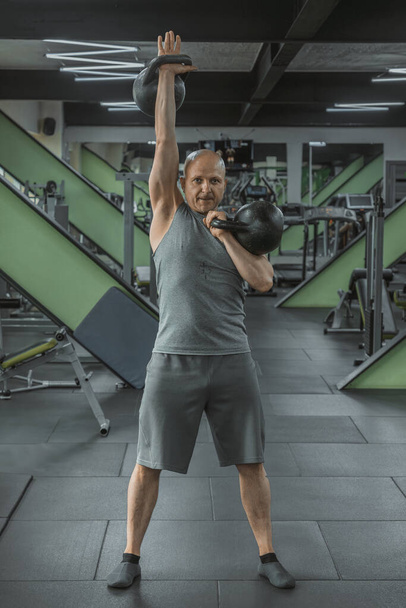 Hombre atleta levanta pesas en el gimnasio - Foto, imagen