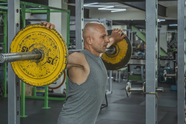 Athletic man doing barbell squats in the gym. Portrait - Photo, Image