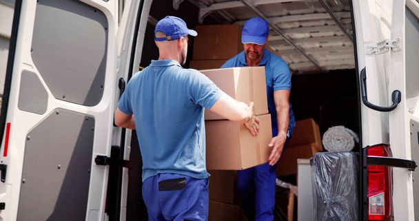 Male Movers In Uniform Loading Delivery Truck - 写真・画像