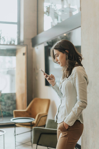 Boční pohled fotografie ohromující brunetka dívka kontrolu jejího telefonu, zatímco si pauzu od práce - Fotografie, Obrázek