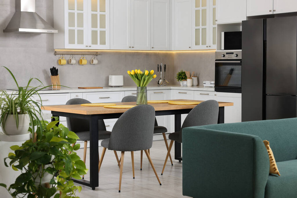 Spring atmosphere. Stylish kitchen interior with comfortable furniture and bouquet of beautiful yellow tulips - Foto, Bild
