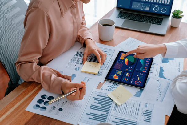 Analyst team colleague discuss financial data on digital dashboard, analyzing charts graph display on laptop and tablet screen. Modern office use business intelligence to plan marketing. Enthusiastic - Photo, Image