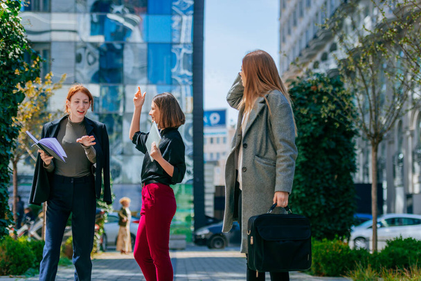 Drie zakenvrouwen hebben een zakelijk gesprek in de stad - Foto, afbeelding