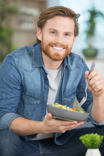happy young man eating a salad - 写真・画像