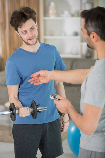 aregiver with young man doing exercise at home - Photo, Image