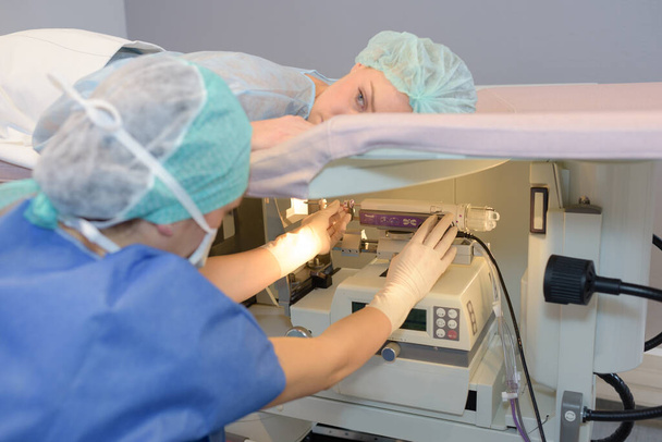 Woman layed on hospital stretcher above diagnostic machine - Foto, Bild