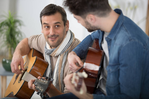 father teaching teenage son the guitar - Foto, afbeelding