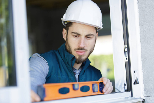 young male worker checks the level of a window - Foto, Imagen