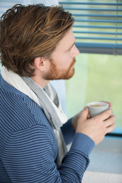 handsome man standing by window and holding coffee cup - Foto, Imagem