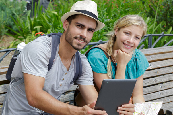 couple are sitting on a bench with a tablet - Foto, imagen