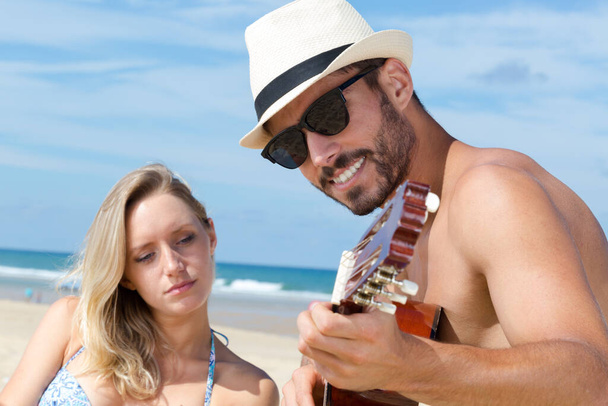 young couple having fun and playing guitar on the beach - Foto, Imagem