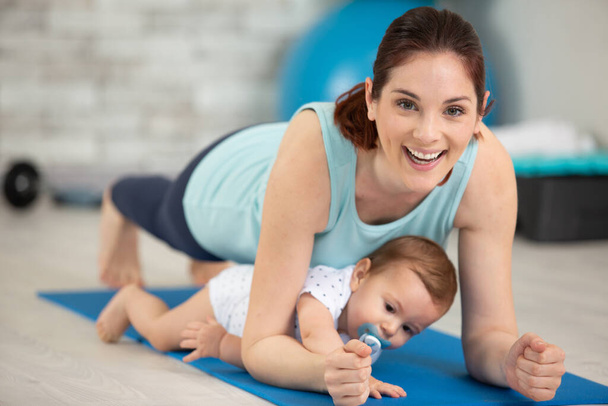 woman ane baby boy exercising on floor at home - Foto, afbeelding
