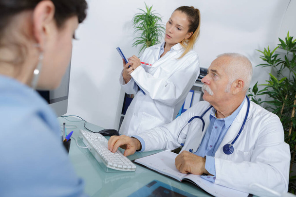 doctor in consultation with patient nurse taking notes - Foto, Imagem