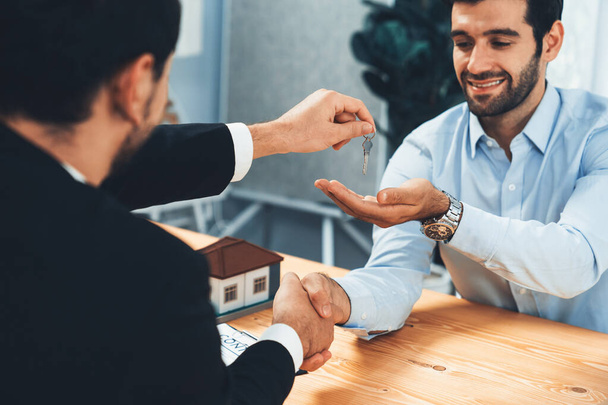 Closeup real estate broker or landlord shake hand with buyer and give a key. Client agree on house loan contract terms. Successful home purchasing deal with real estate agent in office. Fervent - Photo, Image