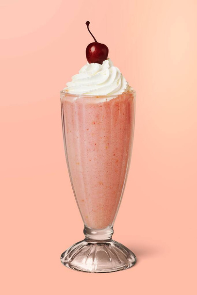Aardbei milkshake met een maraschino kers op achtergrond - Foto, afbeelding