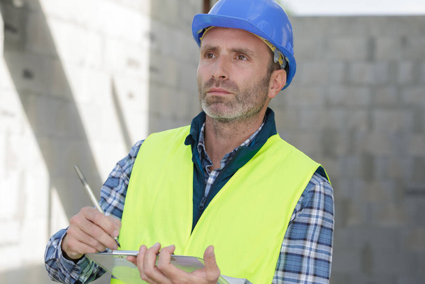 a male builder checking clipboard - Fotoğraf, Görsel