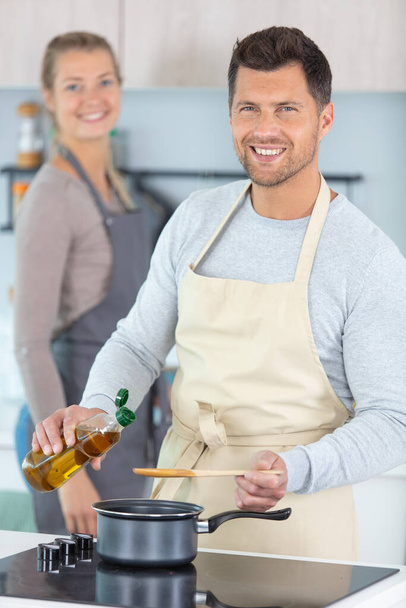 cheerful couple in the kitchen cooking - Foto, Imagen