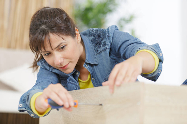 woman is assembling a furniture - Φωτογραφία, εικόνα