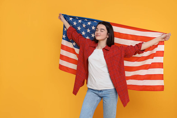 4th of July - Independence Day of USA. Happy girl with American flag on yellow background, space for text - Fotó, kép