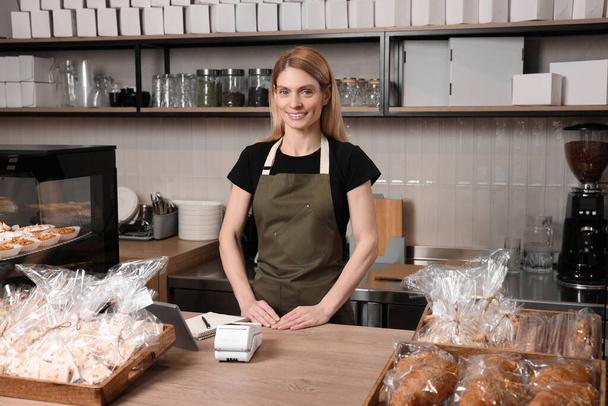 Happy seller at cashier desk in bakery shop - Foto, Imagen