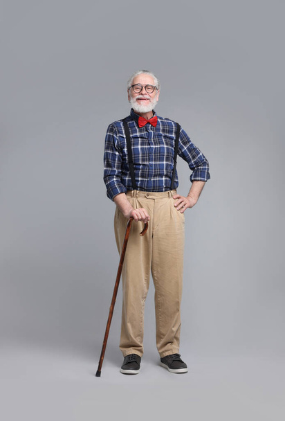 Senior man with walking cane on gray background - Foto, afbeelding